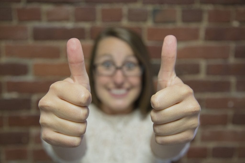 Smiling woman holds two thumbs up