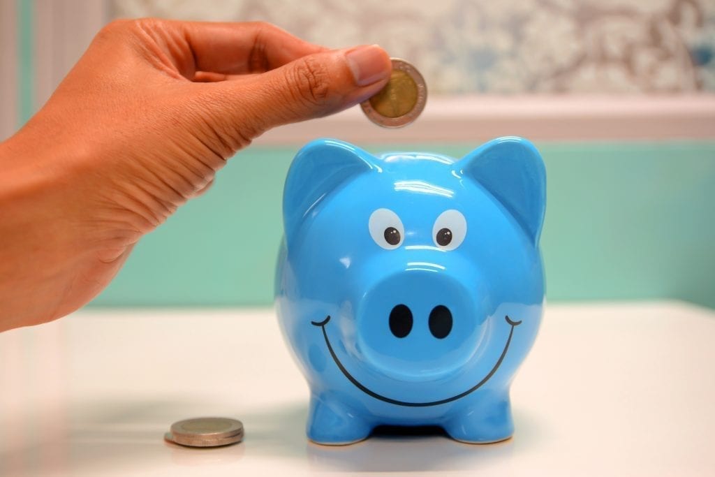 Hand adding coin to piggy bank