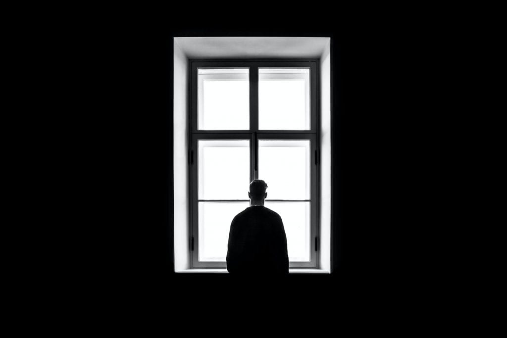 Black and white image of man standing at window