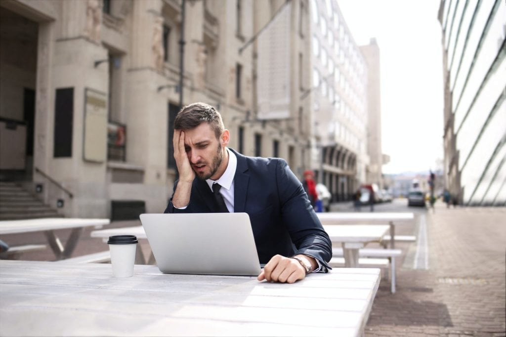 Frustrated man sitting outdoors at a desk