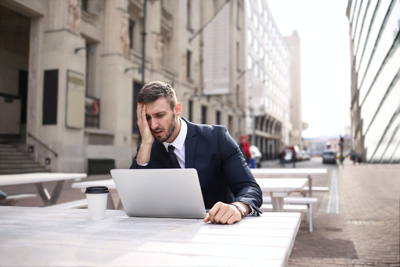 Frustrated man sitting outdoors at a desk