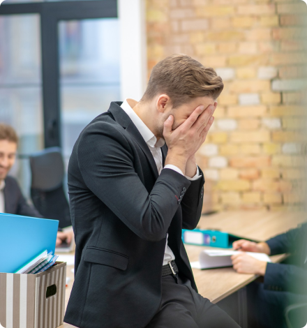 A businessman looking distressed covering his face with both palms