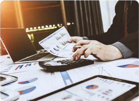 A person engaged in business, utilizing a calculator and a laptop for calculations and data analysis.