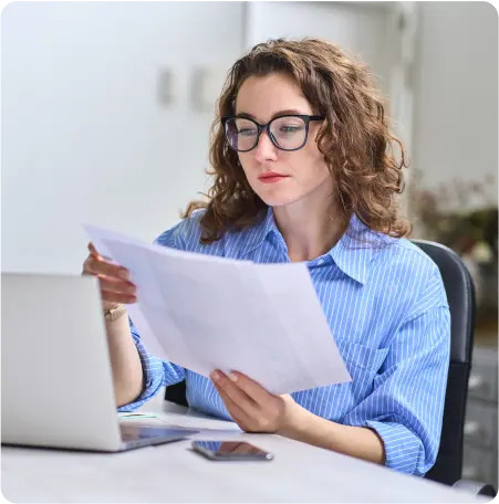 A woman wearing glasses intently examines a document, showcasing her focus and attention to detail.