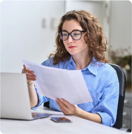 A woman wearing glasses intently examines a document, showcasing her focus and attention to detail.