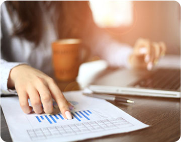 A businesswoman's hand rests on graph paper, indicating analysis and planning in a professional setting.